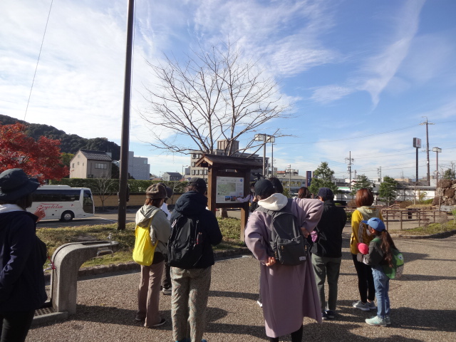 看板の前でコースについて説明している