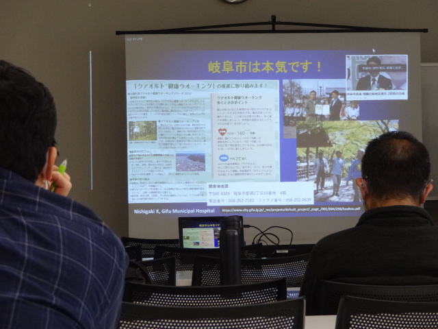 スクリーンに映されている講演の資料を見る参加者