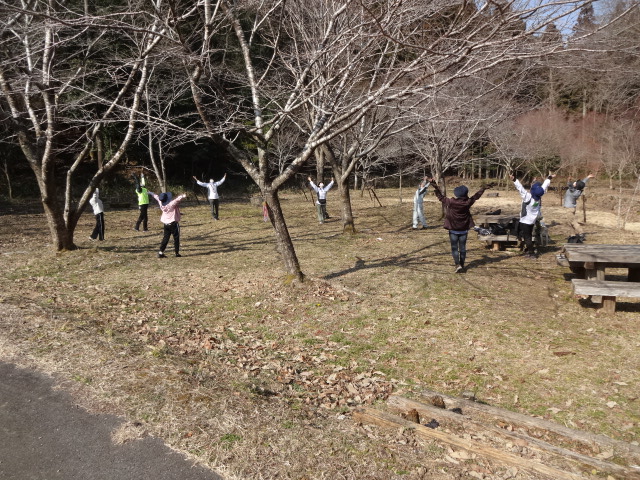 参加者が輪になってストレッチをしている