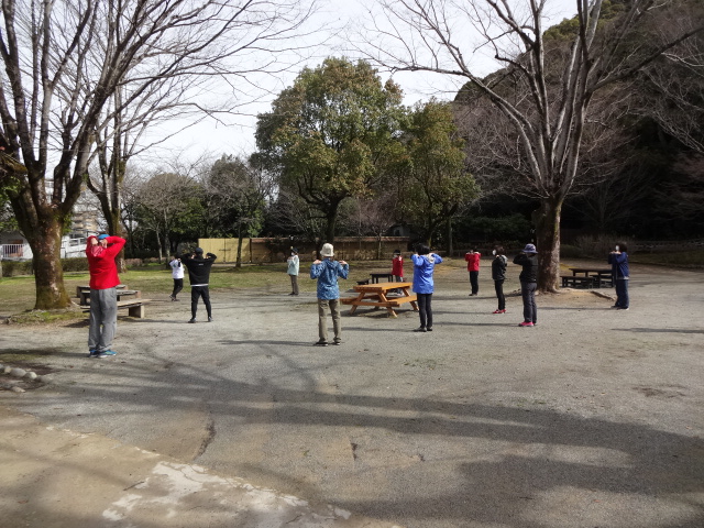 参加者が輪になってストレッチに励んでいる