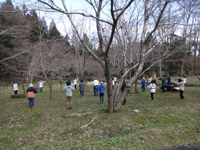 屋外で参加者が出発前のストレッチをしている