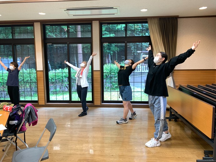 屋内で腕を伸ばしてストレッチに取り組んでいる様子