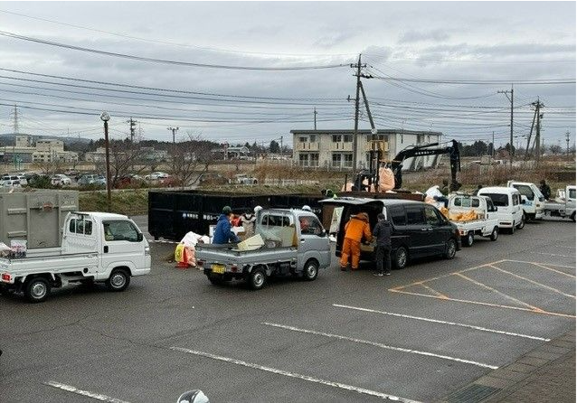 仮置場に災害ごみを運び入れる車両の列の写真