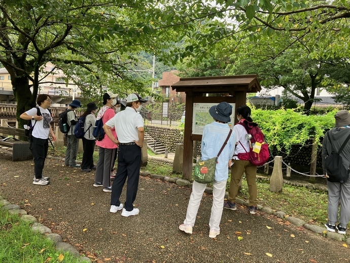 屋外で看板の前に参加者が集まって説明を受けている様子