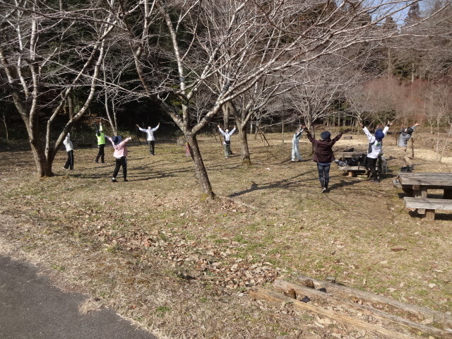 参加者が輪になってストレッチをしている