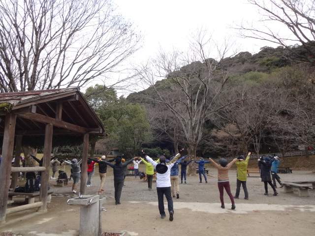 参加者が輪になって腕を伸ばすストレッチをしている